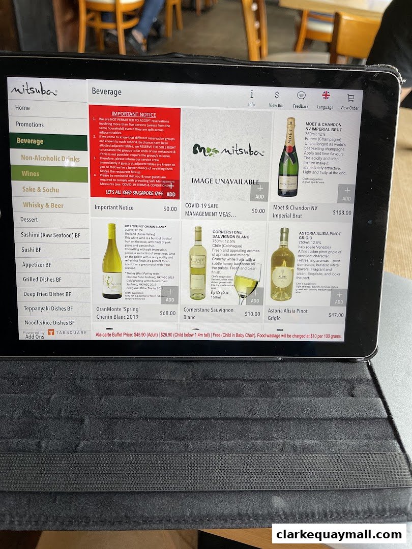A tablet displays the beverage menu for Mitsuba Japanese Restaurant, featuring wines and other drinks.
