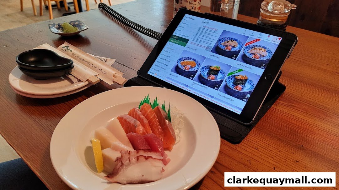A table at Mitsuba Japanese Restaurant with a plate of sashimi and a tablet displaying the menu.