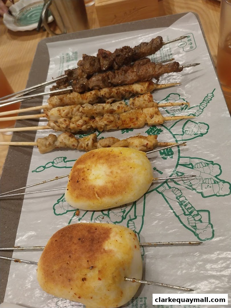 A tray of assorted grilled skewers and fried buns, presented on a paper liner.