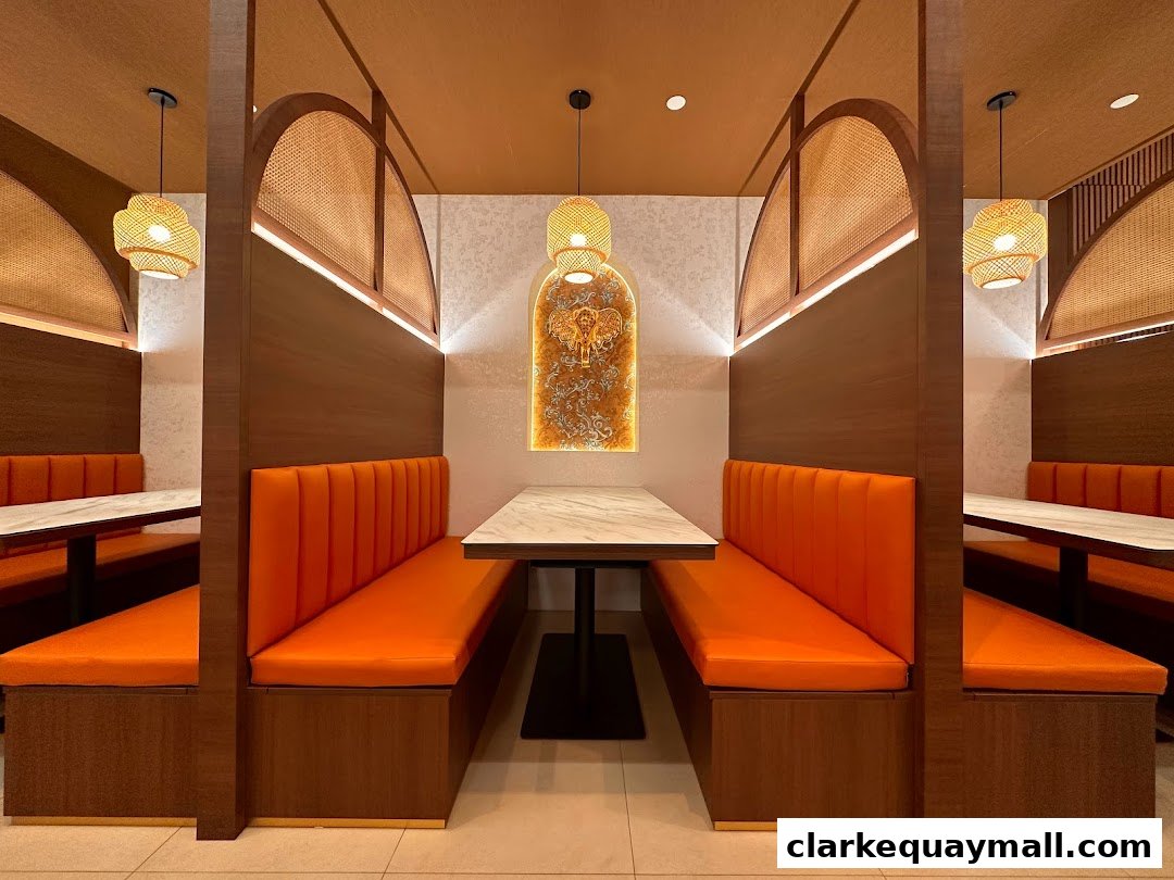 Interior view of a Thai restaurant with orange booth seating and rattan accents.