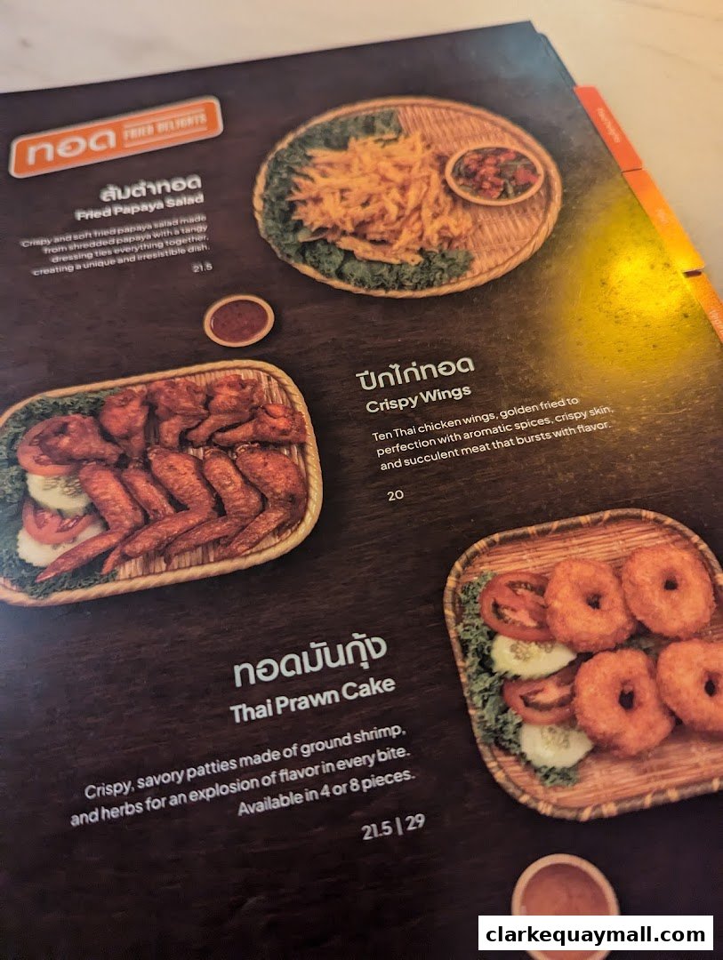A menu featuring Thai dishes like fried papaya salad, crispy wings, and Thai prawn cakes.
