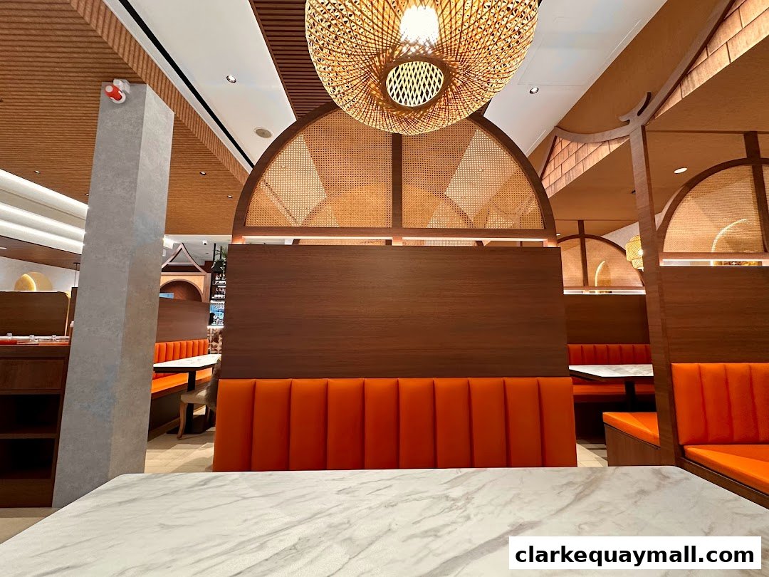 Interior view of Nana Thai Royale Clarke Quay with orange booth seating and wooden accents.
