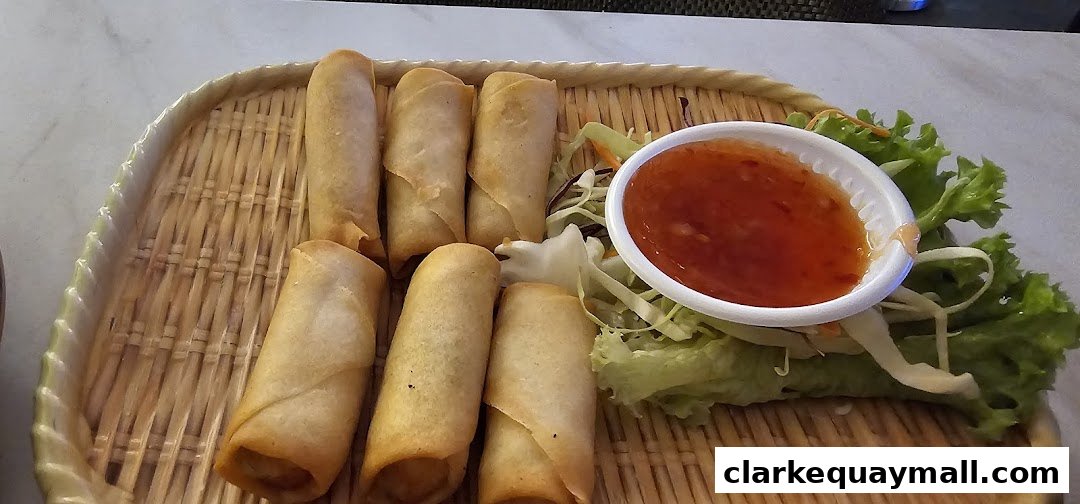 A basket filled with golden-brown spring rolls served with a side of sweet chili sauce and fresh lettuce.