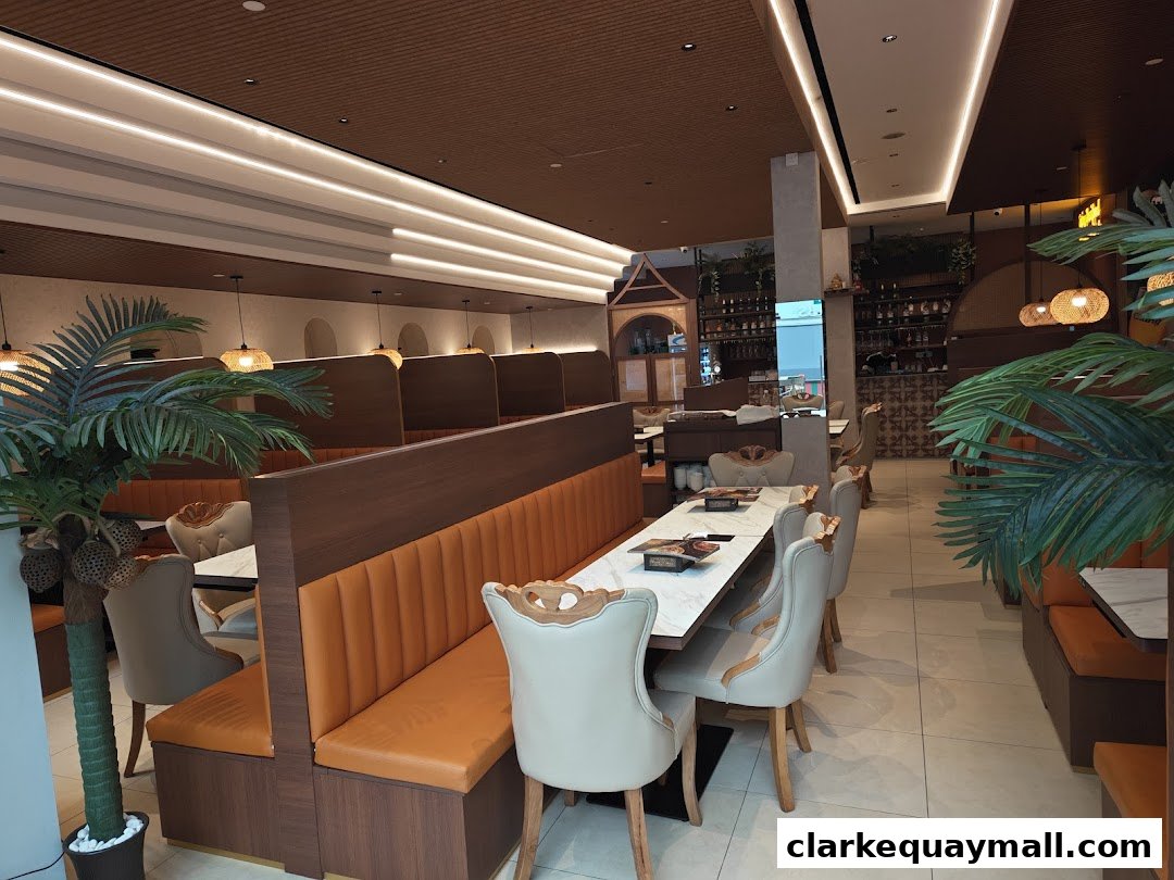 Interior view of a Thai restaurant with booth seating, tables, and decorative plants.