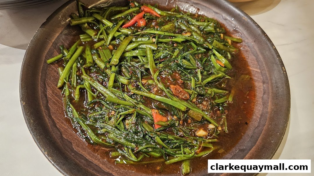 A close-up shot of stir-fried water spinach with chili and garlic in a savory sauce.