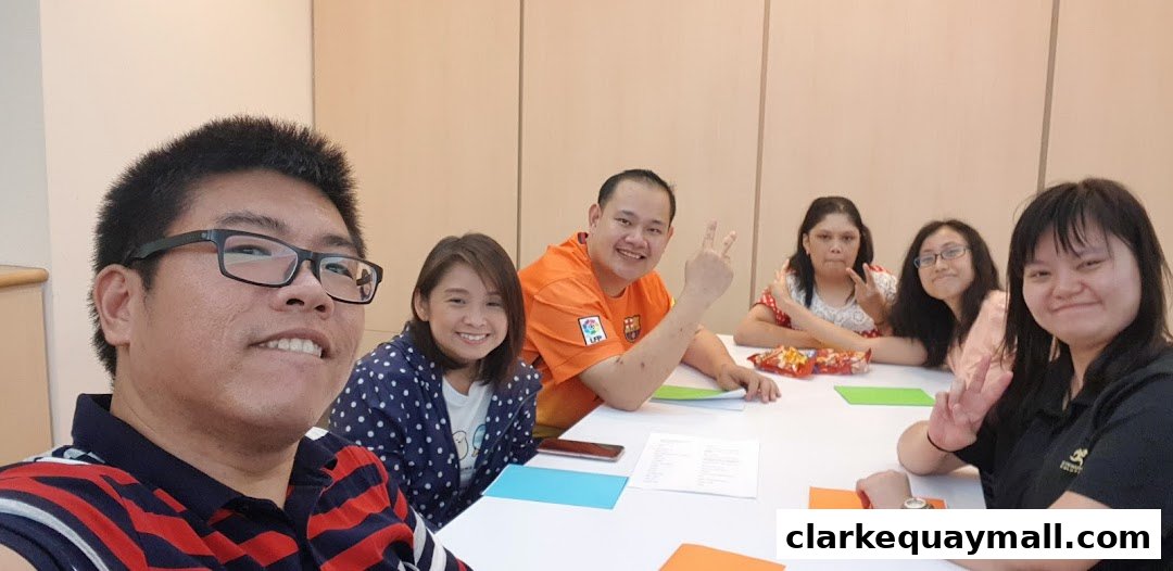 A group of six people smiling and posing for a selfie at a table.