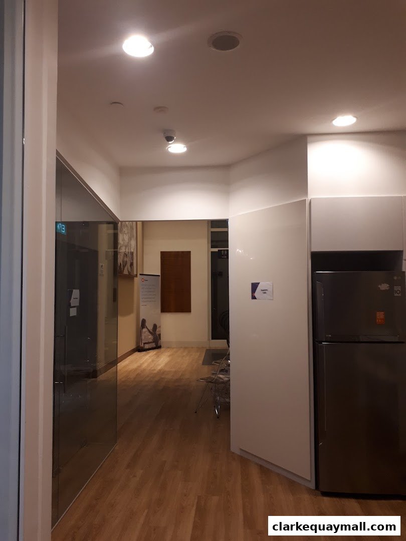 Interior view of a modern office space with a hallway, glass doors, and a refrigerator.