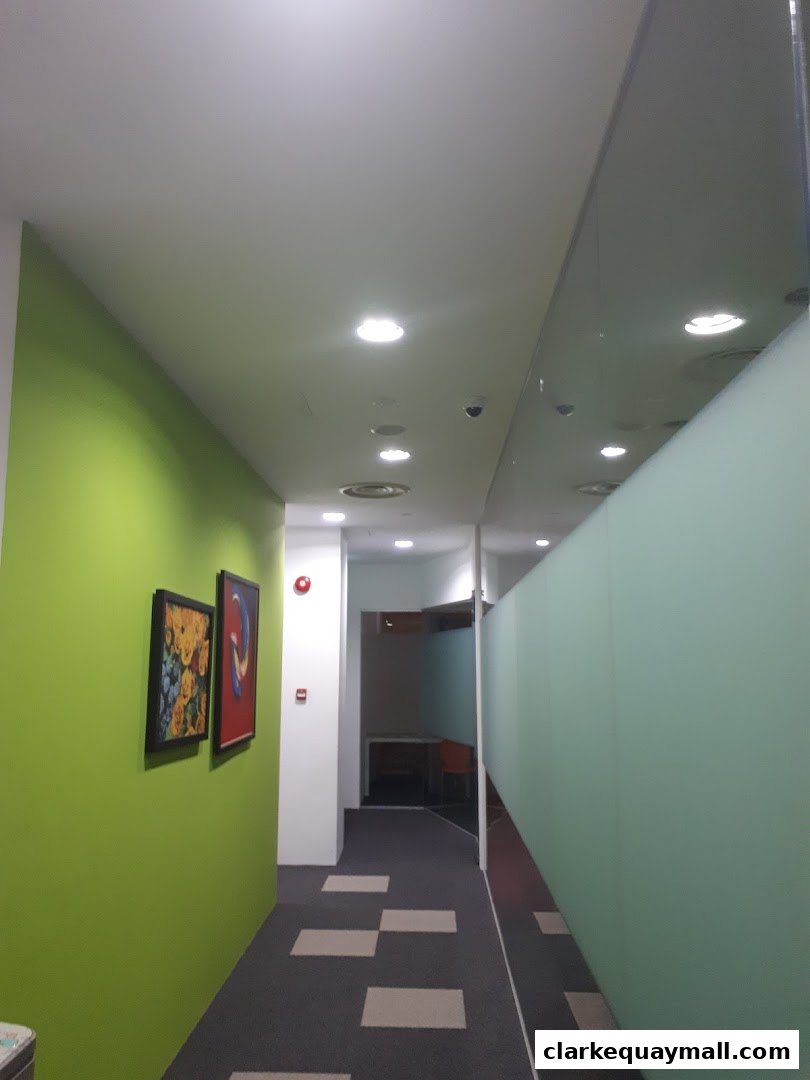 A modern office hallway with green walls, artwork, and frosted glass partitions.