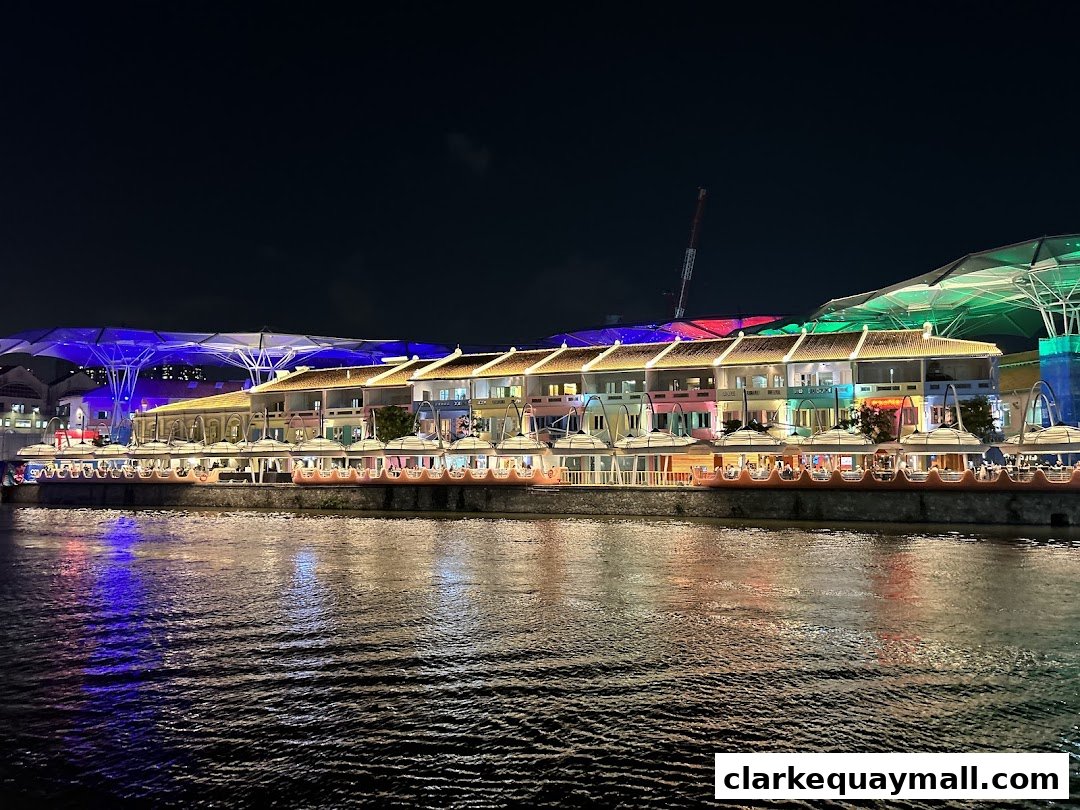 A row of colorful buildings along a riverfront at night, illuminated by lights.