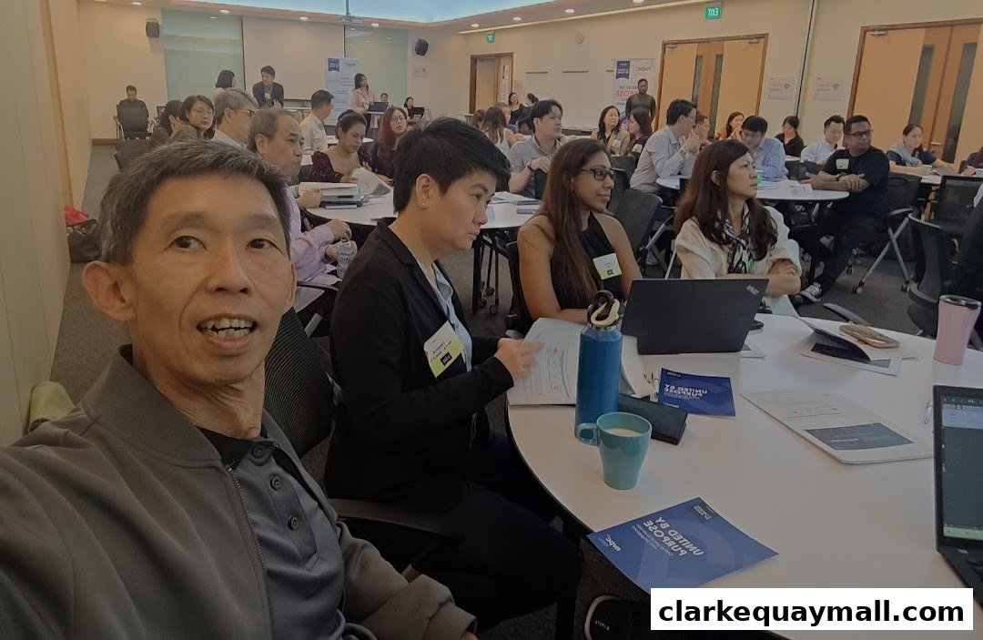 A group of people attending a workshop or seminar, with a man taking a selfie in the foreground.