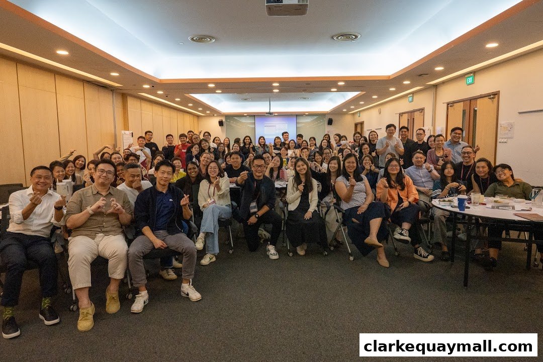A large group of people posing for a photo in a conference room, many making heart gestures.
