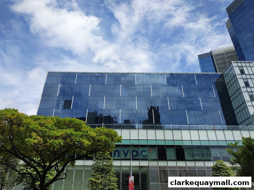 Modern glass-fronted building with trees and blue sky.