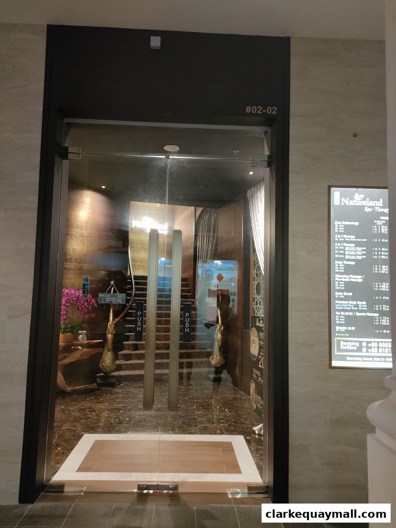 The entrance to Natureland Spa Therapy with glass doors and a price list displayed on the right.