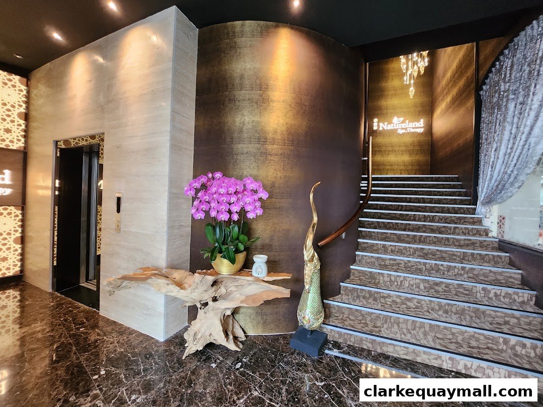 Elegant entrance with stairs, elevator, and floral decor leading to Natureland Spa Therapy.