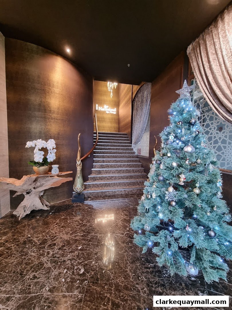 A festive Christmas tree stands beside a staircase leading to the Natureland Spa Therapy entrance.