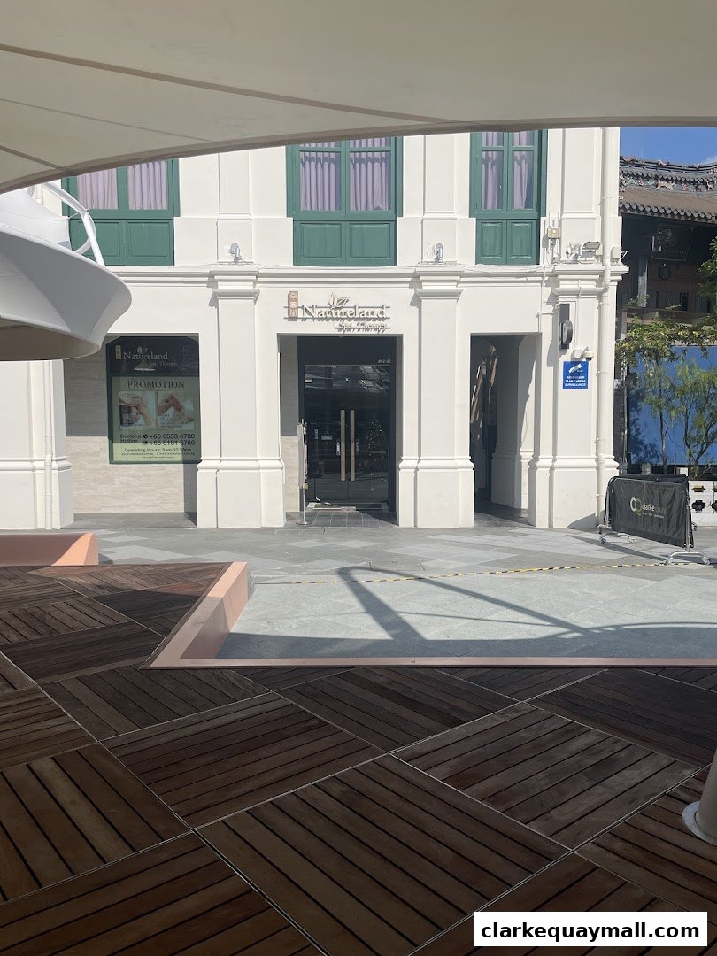 The exterior of Natureland Spa & Therapy at Clarke Quay, featuring its entrance and a promotional poster.
