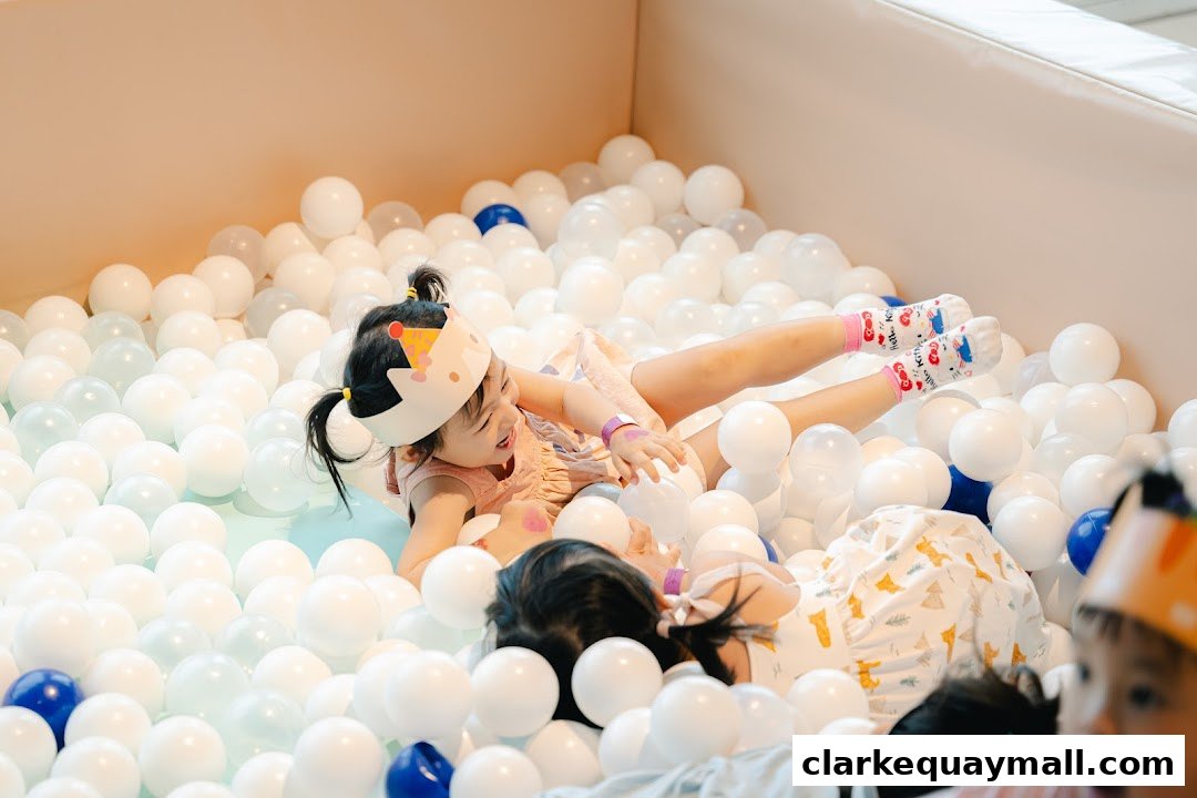 Children playing happily in a ball pit with white and blue balls.