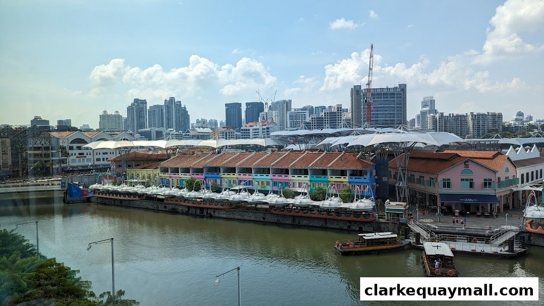 A scenic view of Clarke Quay Central with colorful buildings and boats on the Singapore River.