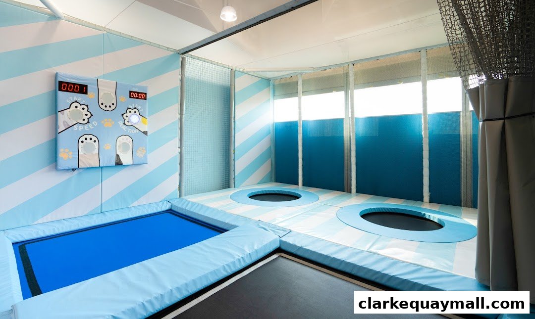 An indoor trampoline park with blue and white striped walls and padded flooring.