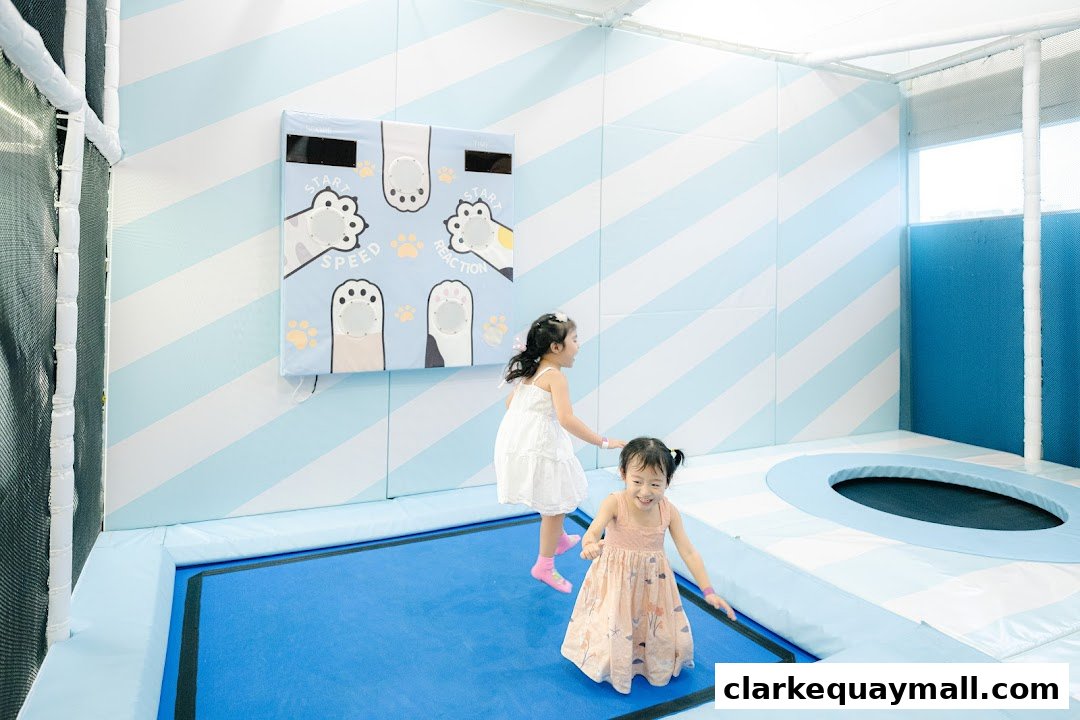 Two young girls playing on a trampoline in a brightly colored indoor play area.