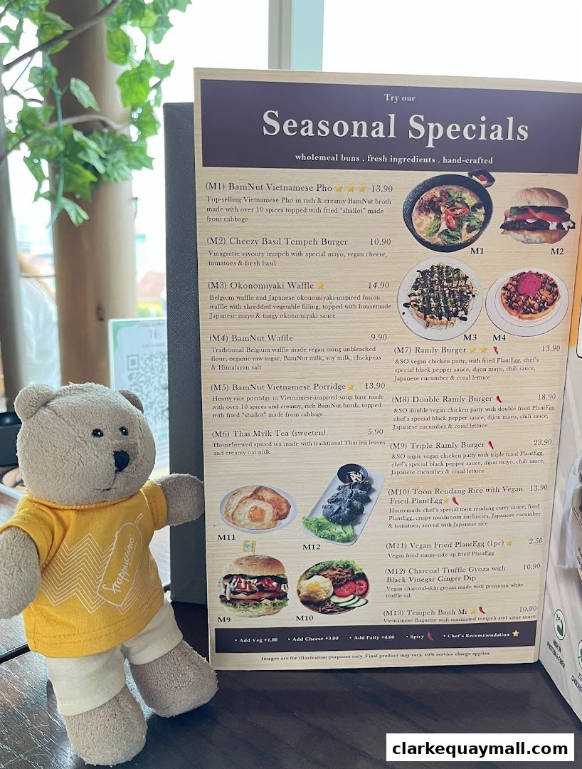 A teddy bear poses next to a menu featuring seasonal specials at nomVnom Bistro.