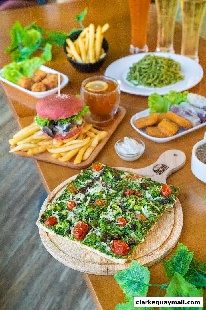 A table laden with delicious plant-based dishes including a burger, fries, pizza, and drinks.