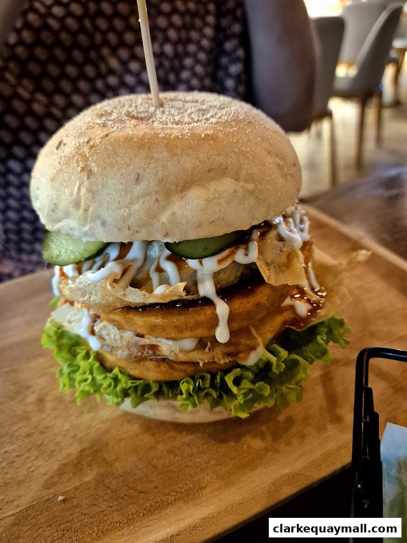A close-up shot of a gourmet burger with lettuce, pickles, and sauce on a wooden board.