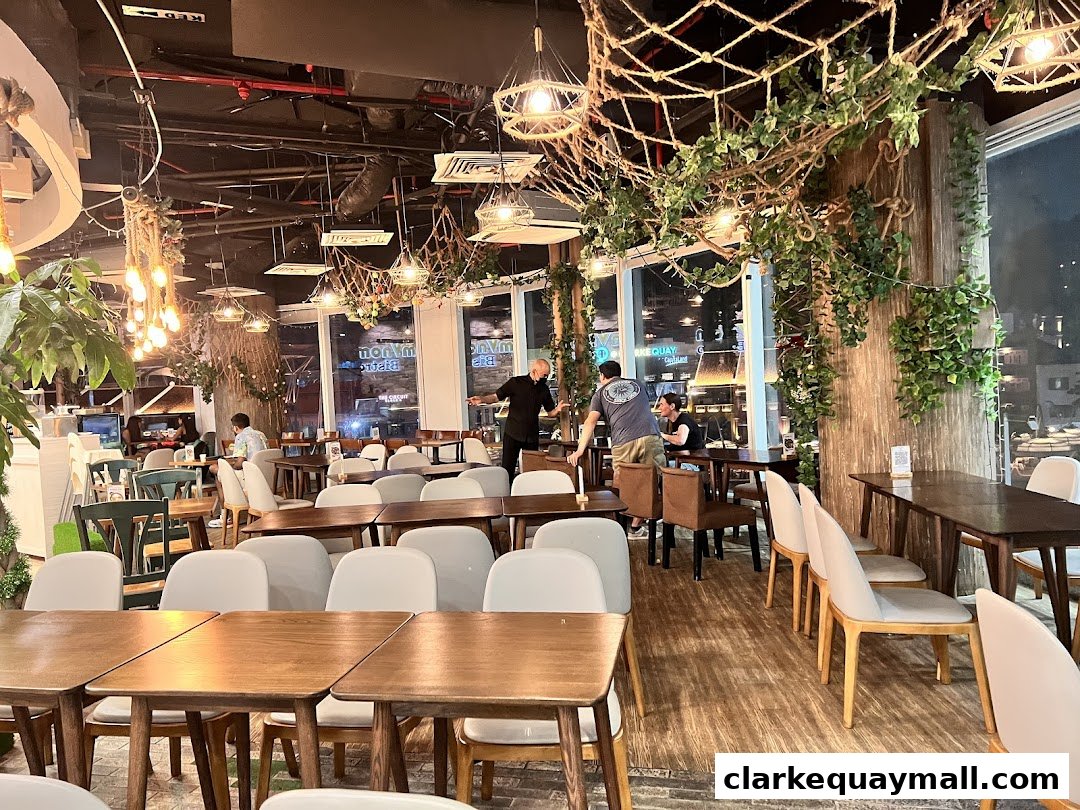 Interior view of a restaurant with wooden tables, chairs, and decorative plants.