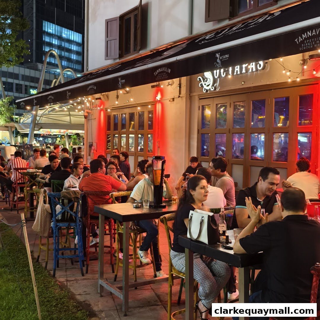 People dining at tables outside an international tapas bar called Octapas at night.