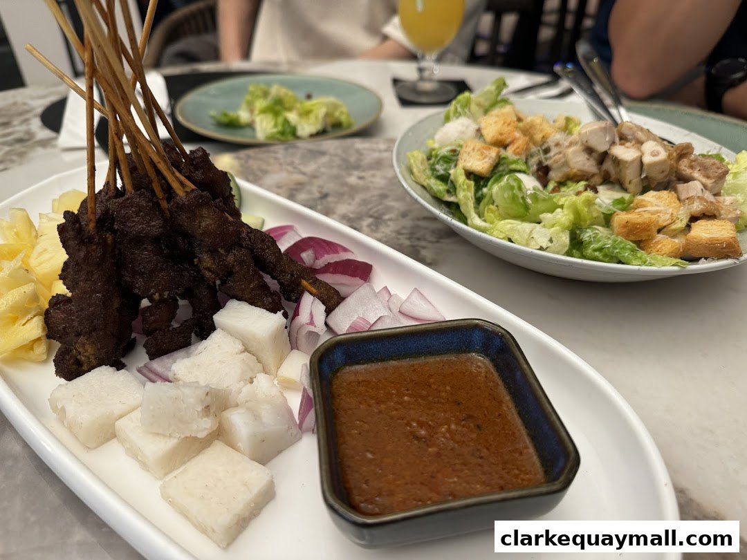 A platter of satay skewers with rice cakes, pineapple, and red onion, served with peanut sauce.