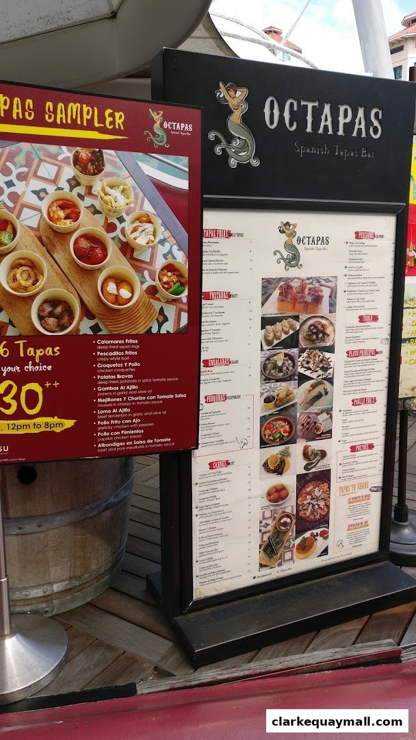 A menu board for Octapas Spanish Tapas Bar, showcasing various tapas dishes and a sampler offer.