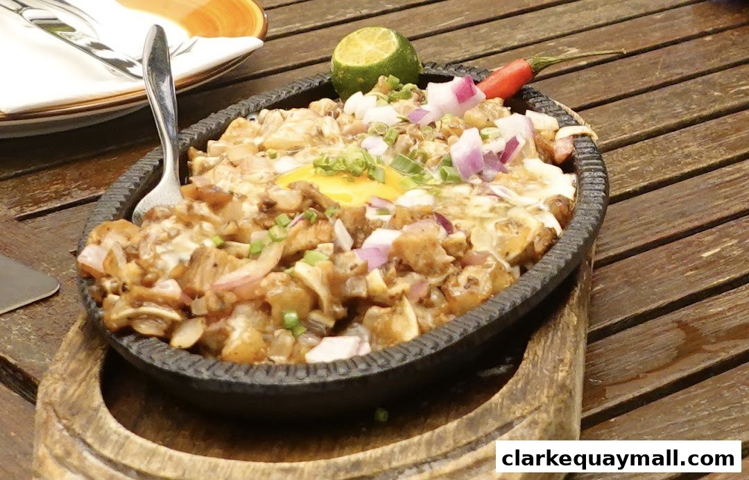 A sizzling plate of tapas topped with egg, onions, and chili, served on a wooden table.