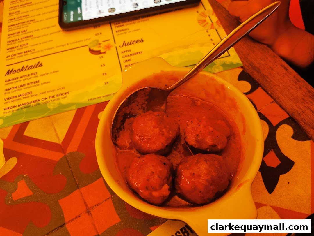 A close-up of a tapas dish with a menu and phone in the background.