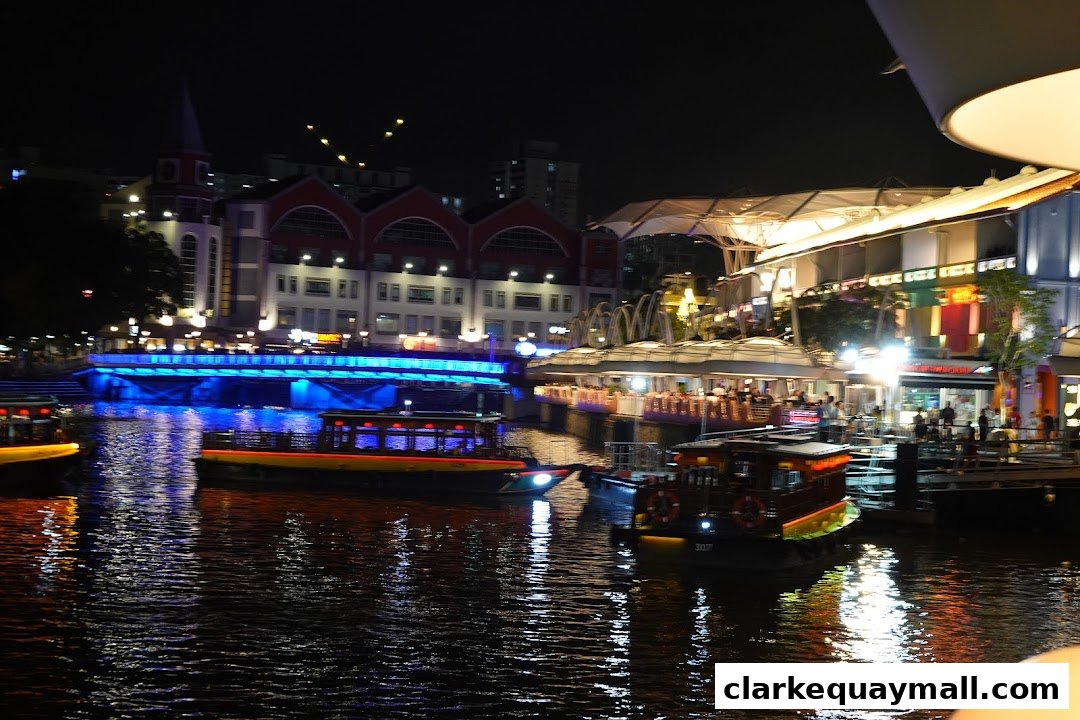 A lively waterfront scene at night with boats on the water and illuminated buildings.