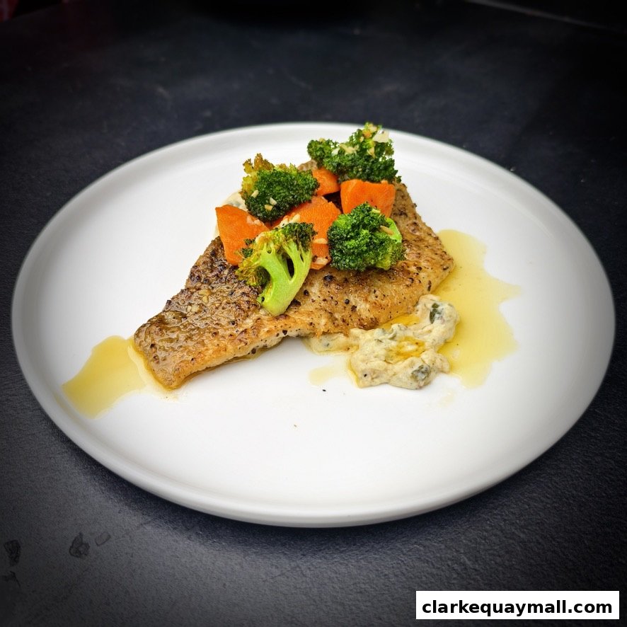 A beautifully plated dish of pan-seared fish with broccoli and carrots, served with a creamy sauce.