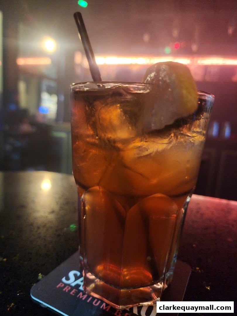 A refreshing cocktail with ice and a lemon wedge on a bar counter.
