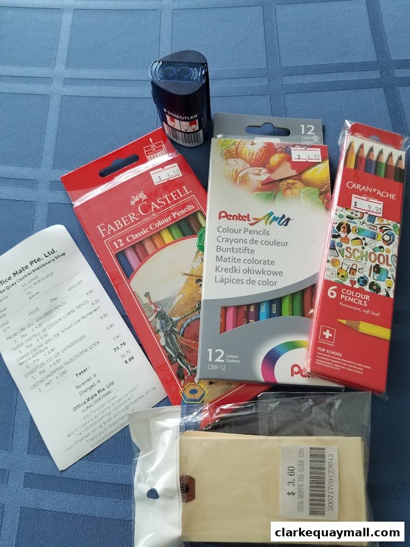 A collection of stationery items including colored pencils, a sharpener, and shipping tags from Office Mate.