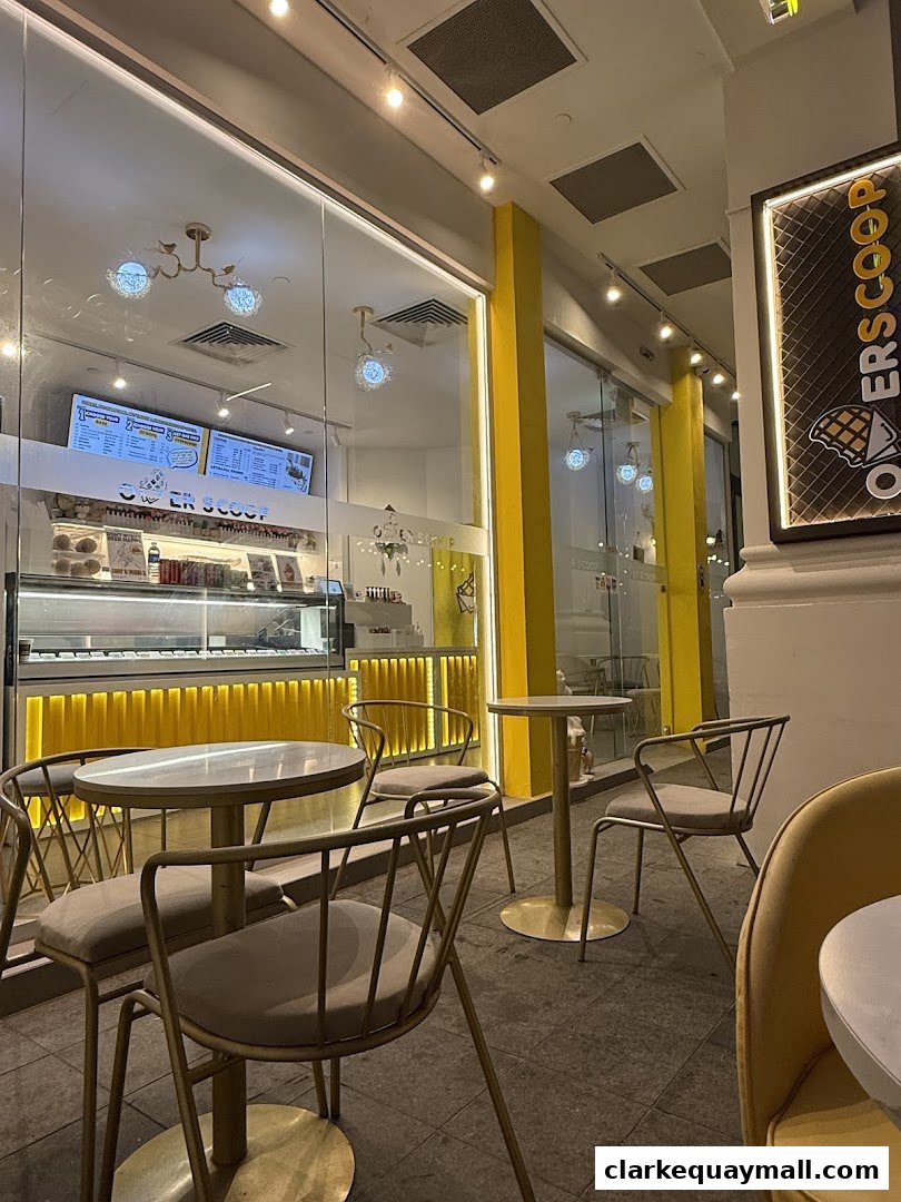 Exterior view of Overscoop CQ Clarke Quay Freshly Made Waffles with seating and illuminated signage.