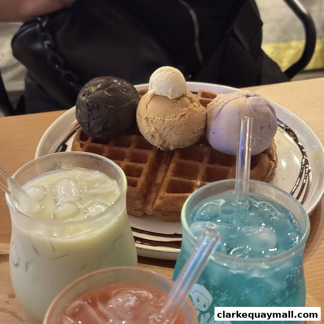 A waffle topped with three scoops of ice cream and three colorful drinks.