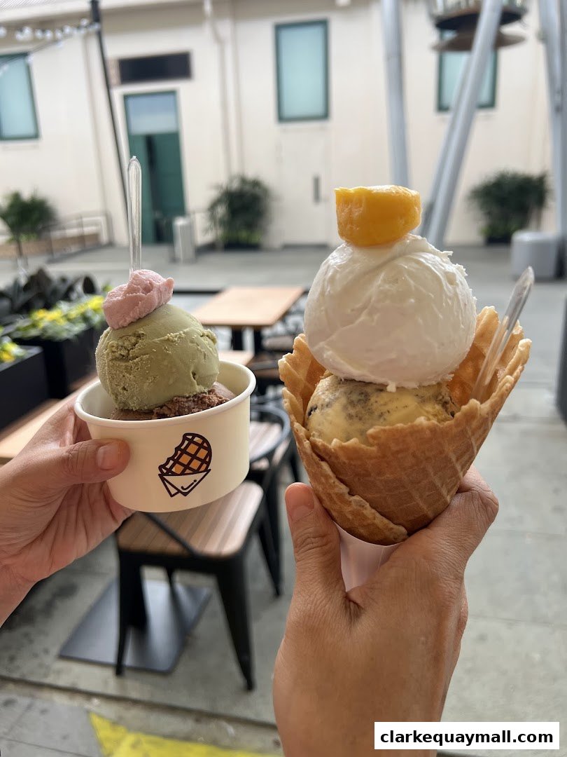 Two hands holding freshly made waffles and ice cream cups.