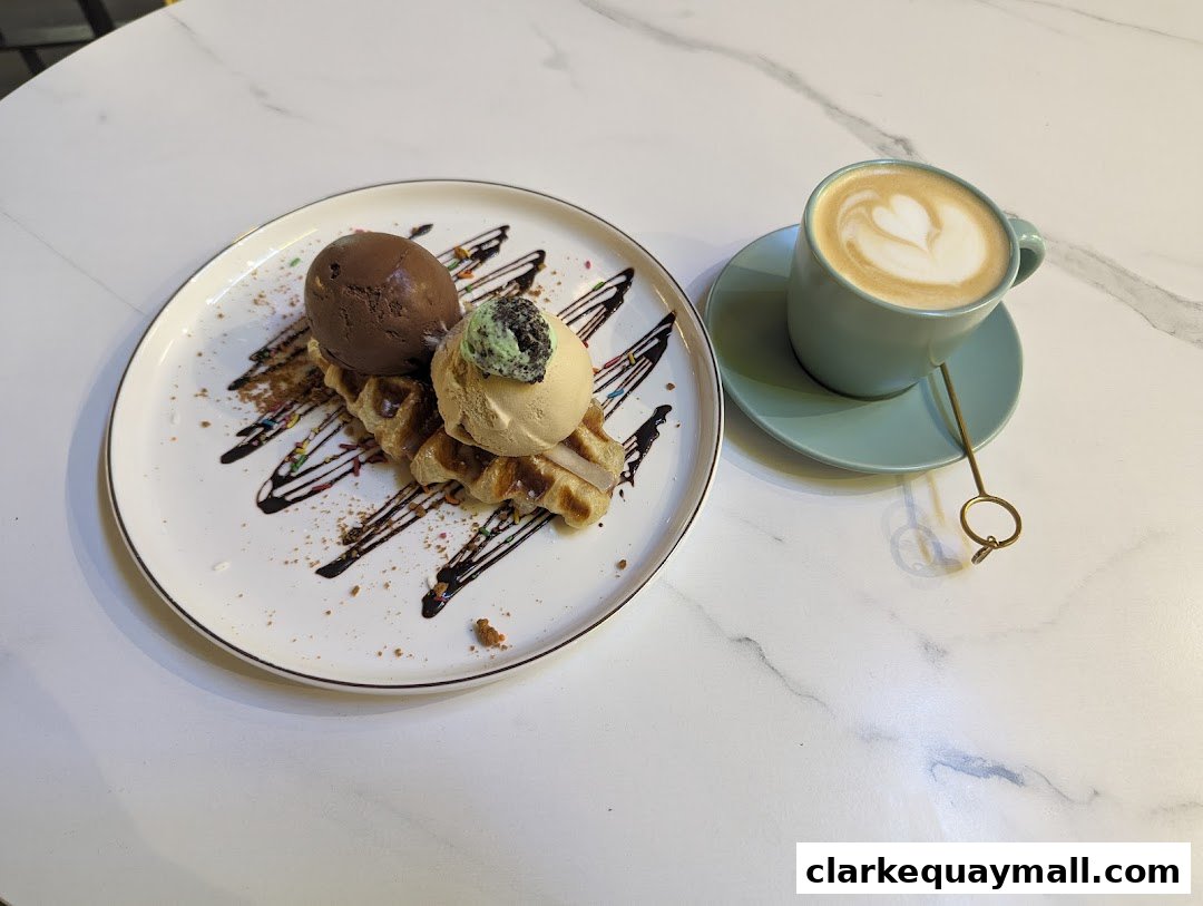 A delicious waffle with two scoops of ice cream and a latte art coffee.