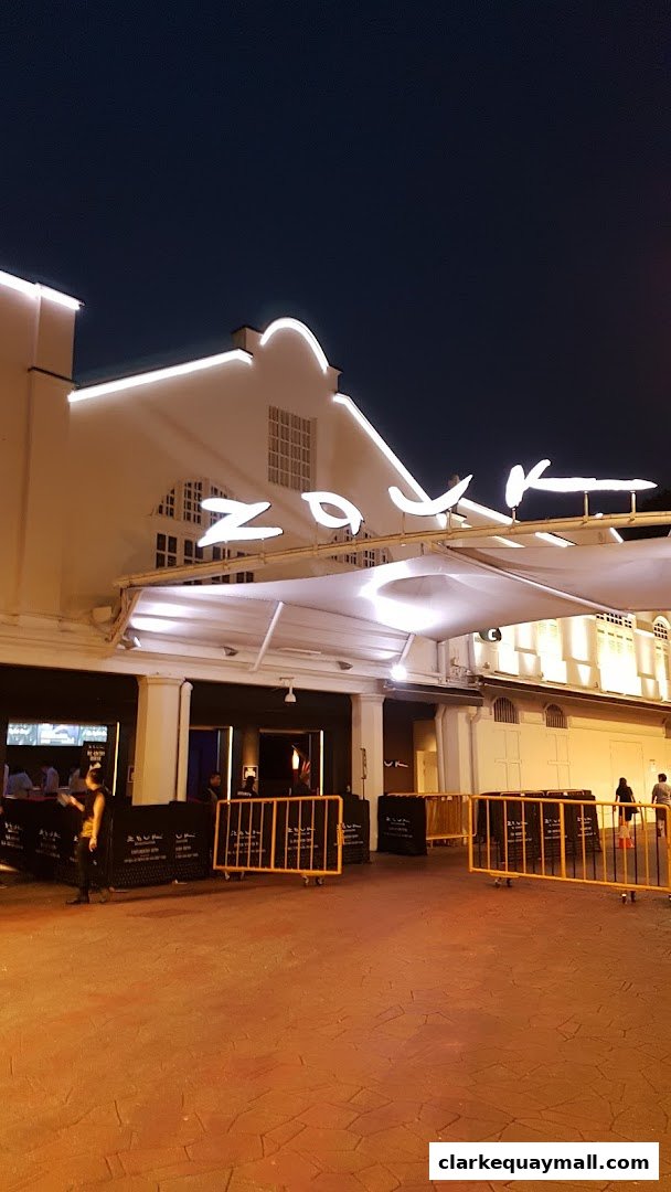 The illuminated exterior of the Phuture shop at night with a canopy and barriers.