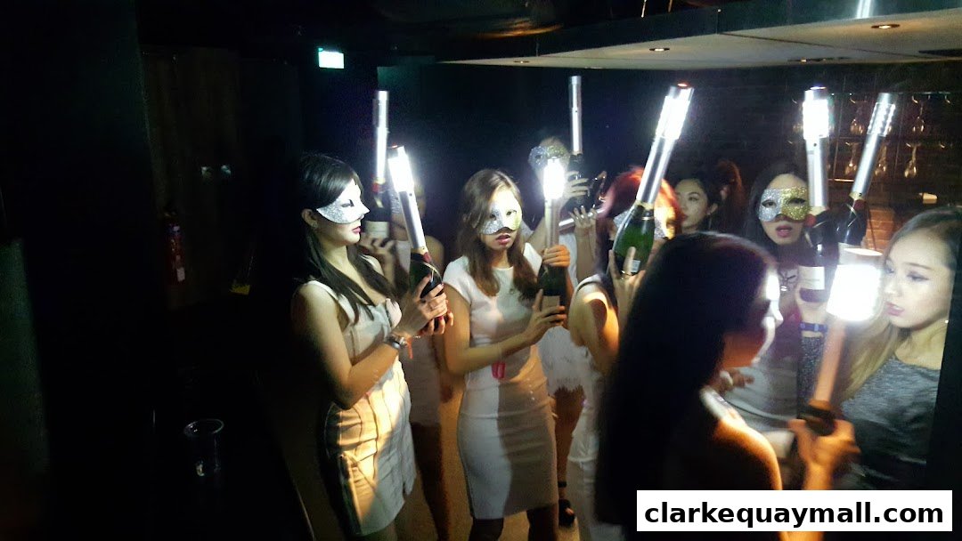 A group of women in masks holding champagne bottles with sparklers at a party.