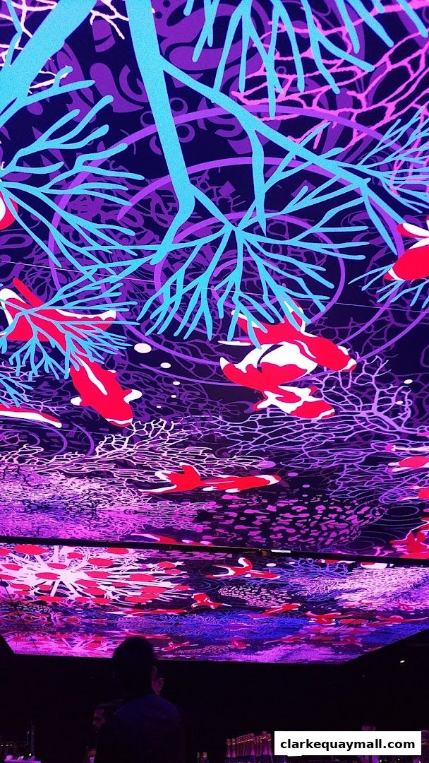 A person looks up at a vibrant ceiling with a koi fish and coral reef design.