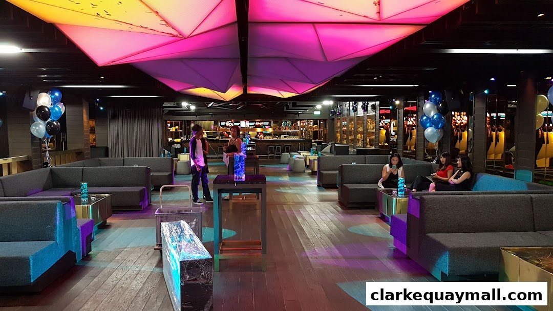Interior of a modern lounge with plush seating, colorful lighting, and a bar in the background.