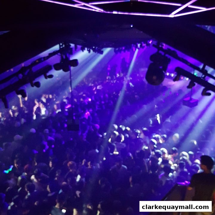 A crowded nightclub with purple lights and a DJ booth visible.