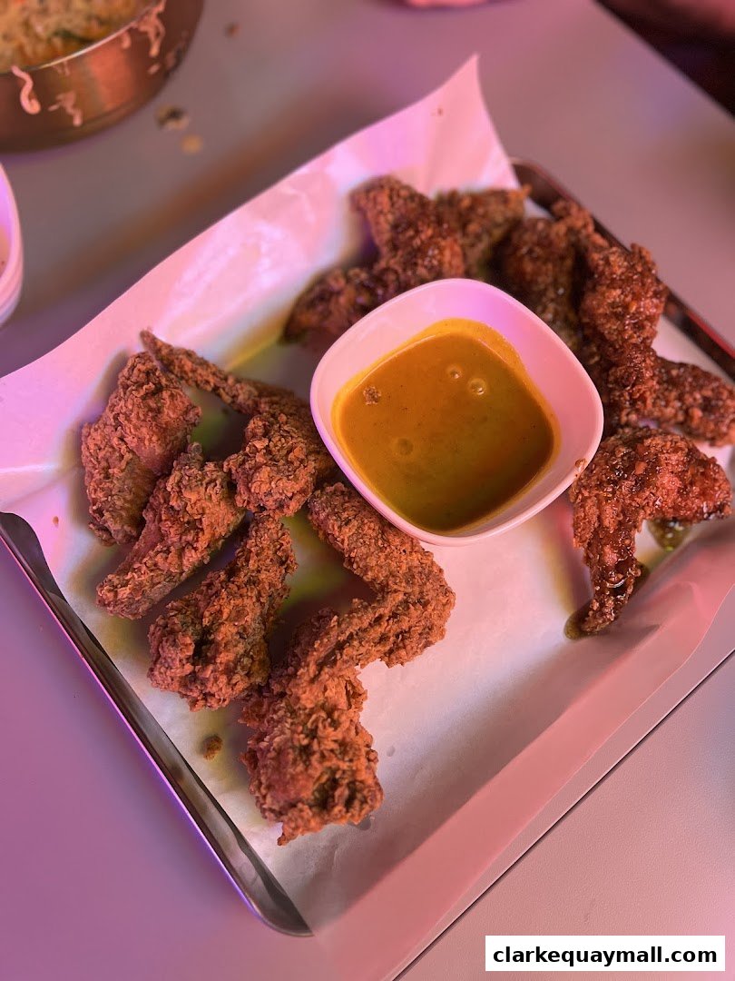 Crispy Korean fried chicken wings served with a dipping sauce on a tray.