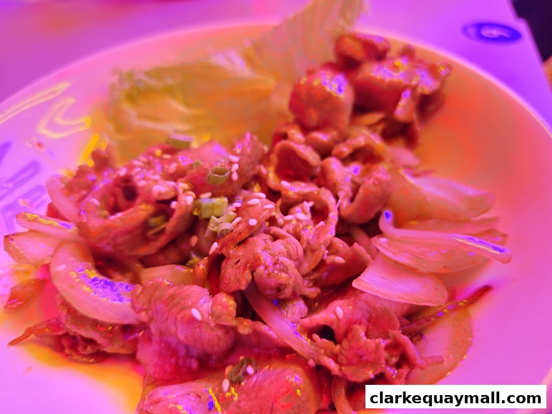 A close-up of a Korean street food dish with thinly sliced meat, onions, and sesame seeds.