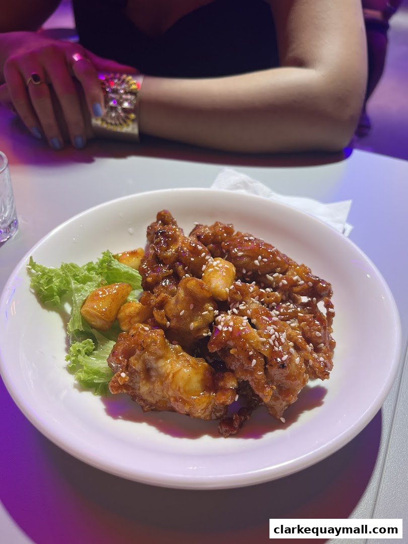A plate of Korean fried chicken with tteokbokki and lettuce, served at a restaurant.