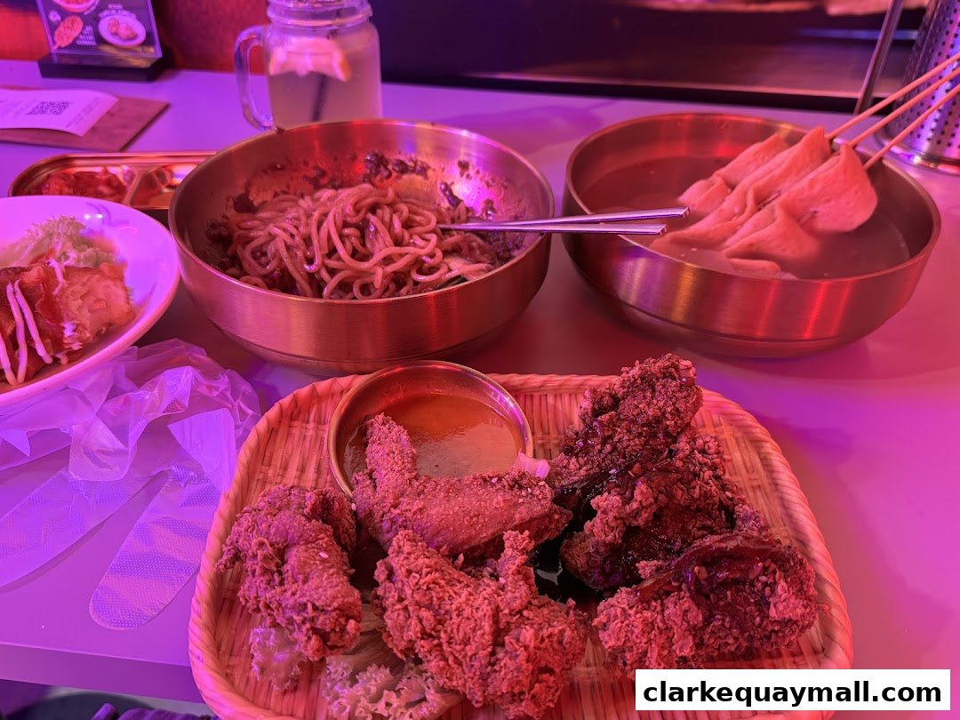 A table laden with Korean street food, including fried chicken, noodles, and fish cakes.